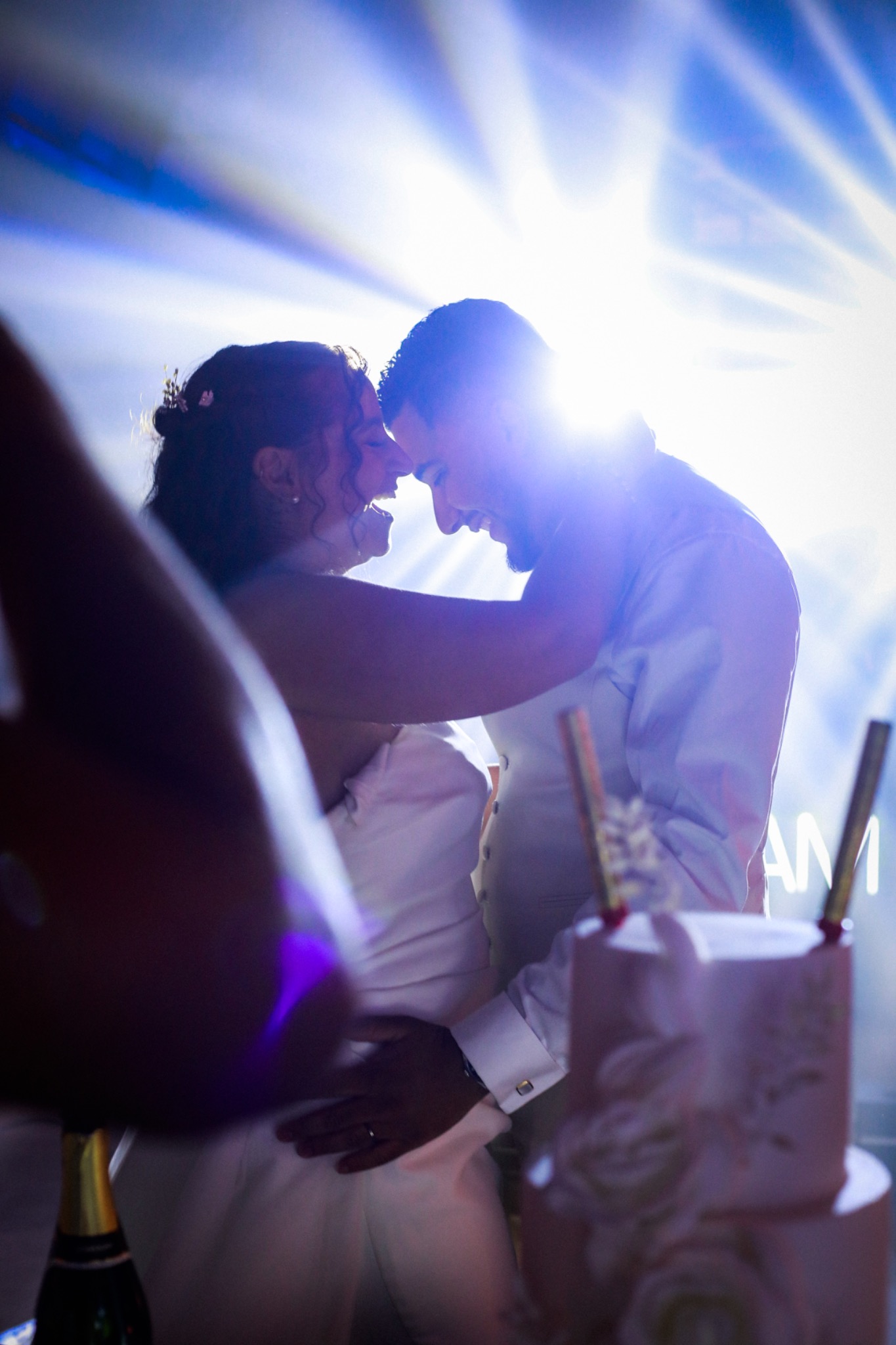 Moment complice des mariés dans les lumières de la soirée